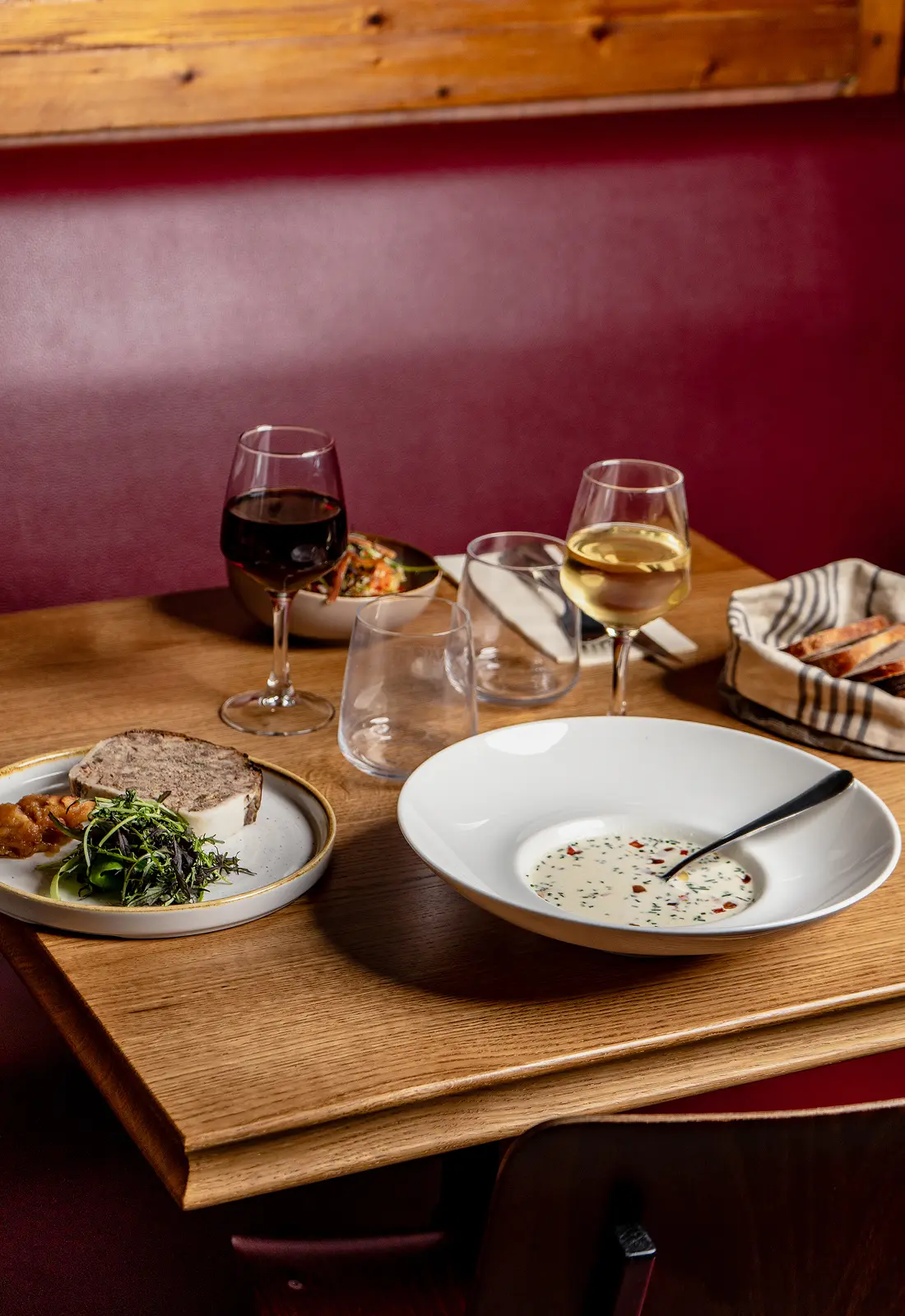 Table dressée avec une soupe, un plat et deux verres de vin