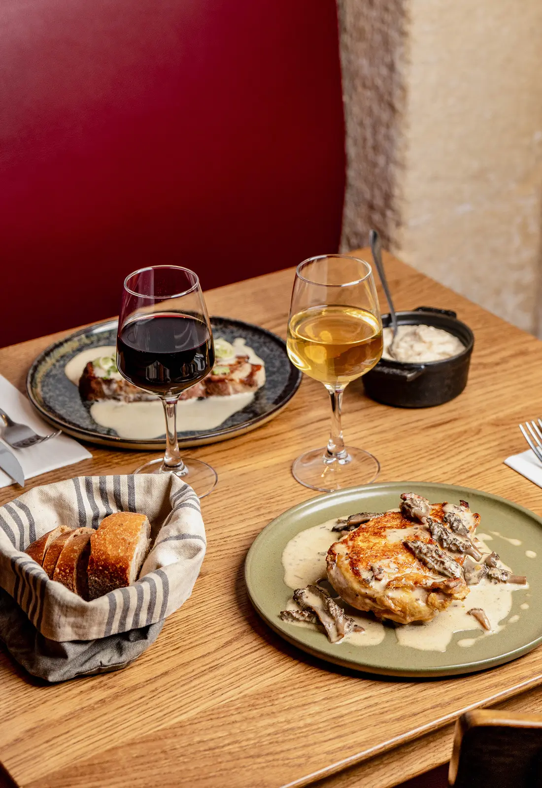 Table avec volaille rôtie, panier de pain et verres de vin