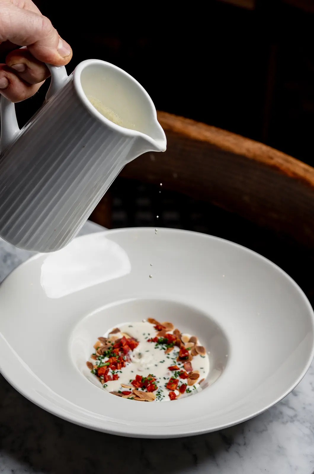 Sauce versée à table sur une assiette creuse garnie