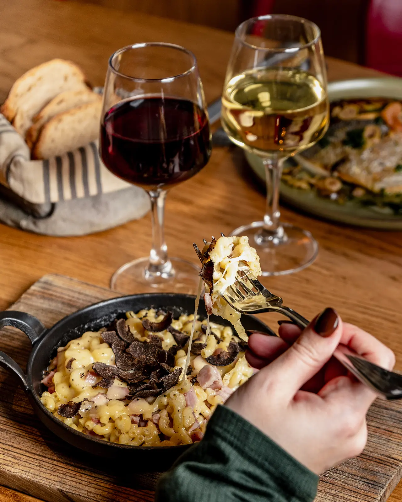 Plat en cocotte et verres de vin rouge et blanc sur une table en bois
