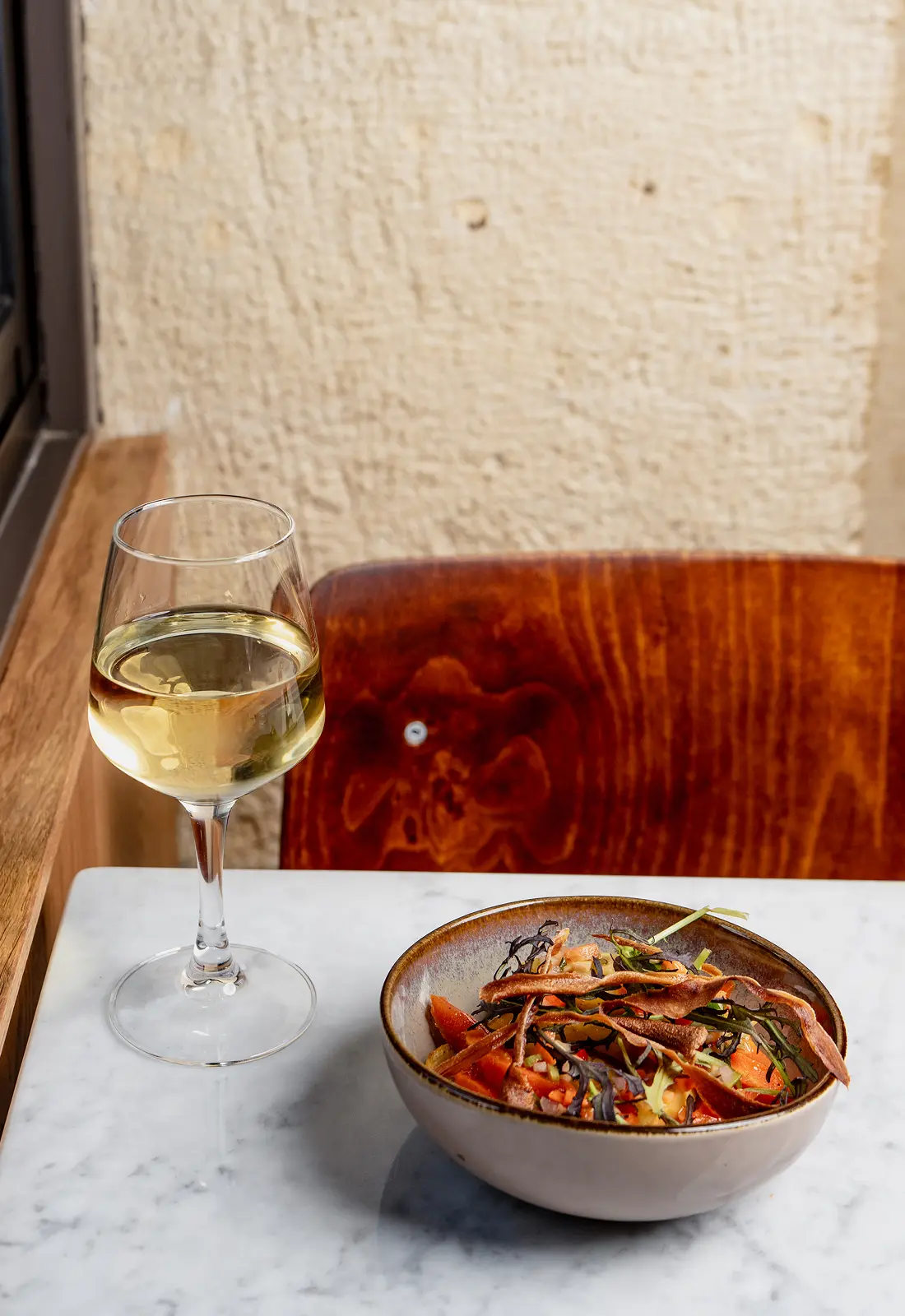 Plat mijoté et verre de vin blanc sur une table en marbre